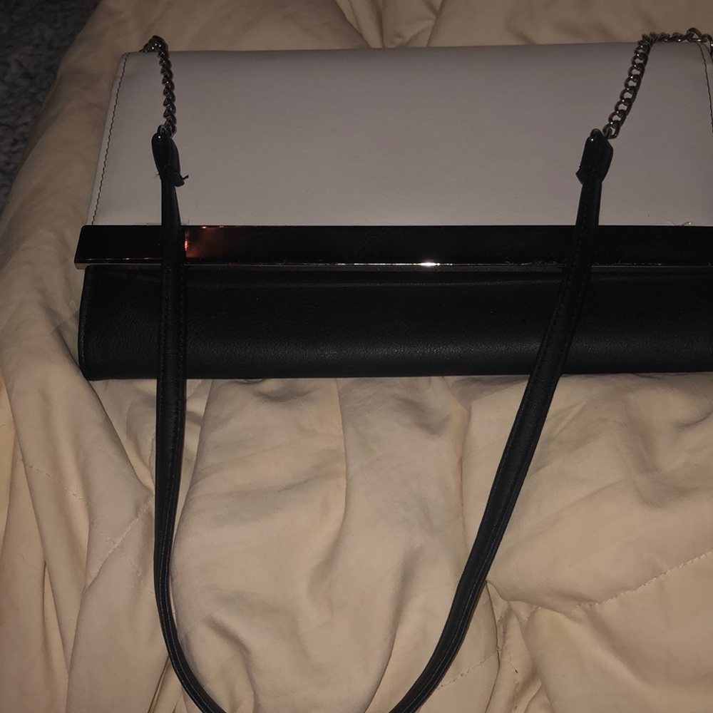 Bland and white purse with strap included has one pocket black on the inside